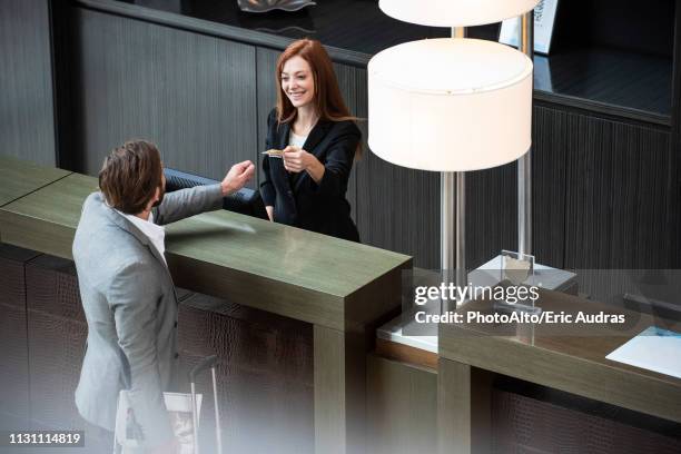 female receptionist giving credit card to businessman - accueil hotel photos et images de collection