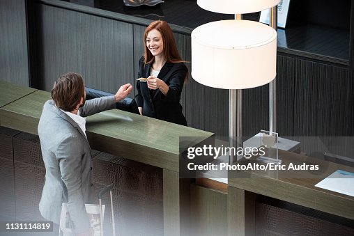 Female receptionist giving credit card to businessman Female receptionist giving credit card to businessman