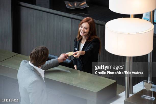 female receptionist giving credit card to businessman - debit cards credit cards accepted stock pictures, royalty-free photos & images