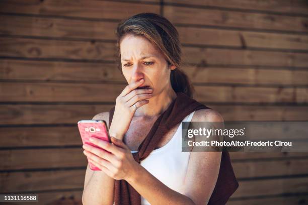 serious mature woman looking at smart phone - scandal stock-fotos und bilder