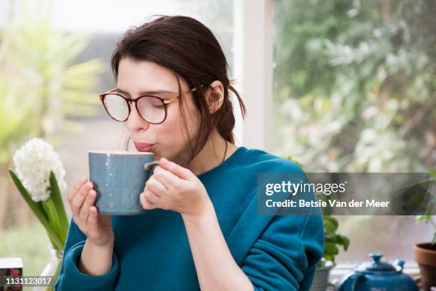 woman is blowing into hot drink, eye glasses are steamed up. - steamed stock pictures, royalty-free photos & images