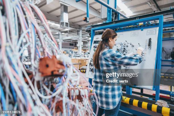 ouvrier manuel féminin travaillant sur la ligne de production en usine - harnais de sécurité photos et images de collection