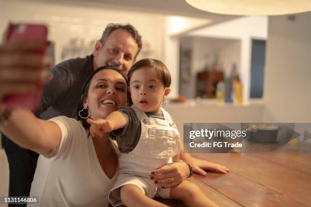 familie met downsyndroom zoon met behulp van mobiele thuis - down syndrome baby stockfoto's en -beelden