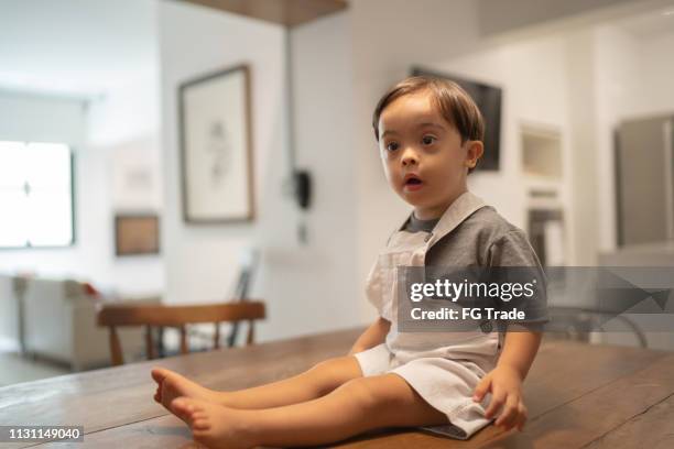 down syndrome little boy sitting on dinning table - down syndrome baby stock pictures, royalty-free photos & images