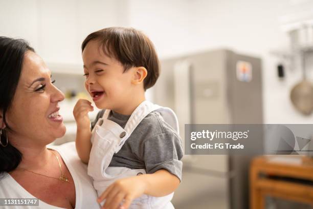mother and down syndrome son embracing at home - down syndrome baby stock pictures, royalty-free photos & images