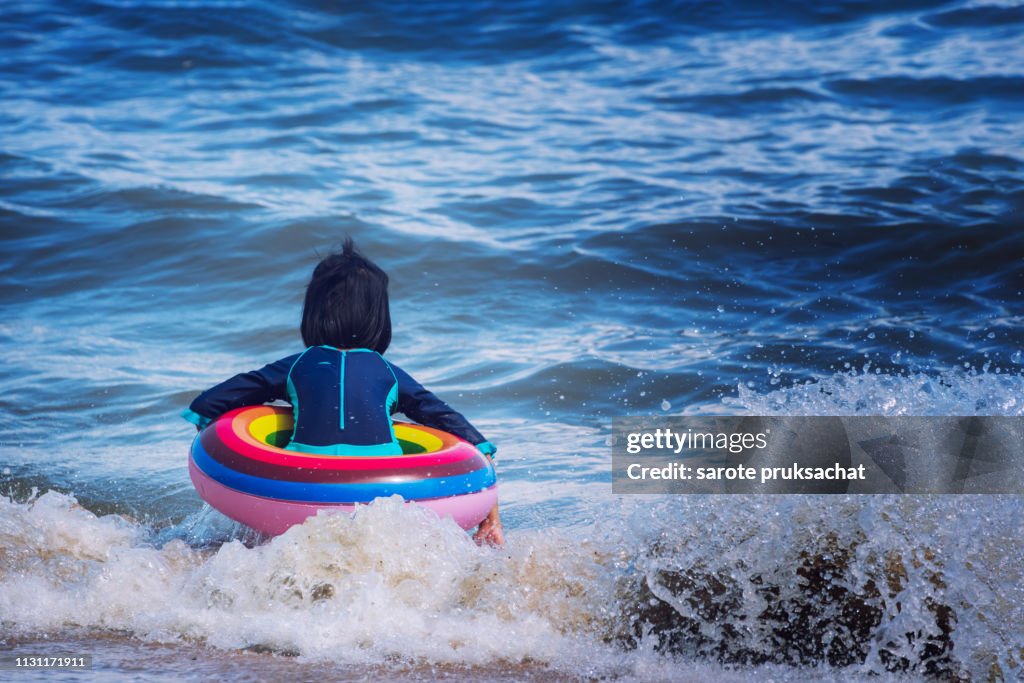 Safety equipment, child playing at beach with lifebuoys.