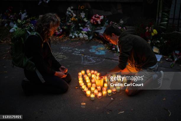 People light candles next to flowers and tributes laid by the wall of the Botanic Gardens on March 17, 2019 in Christchurch, New Zealand. 50 people...