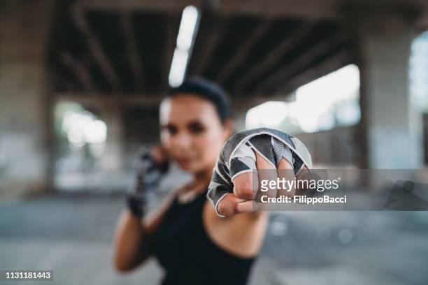 poderosa mujer joven golpeando - combat sport fotografías e imágenes de stock