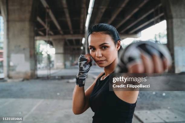 powerful young woman punching - arts martiaux stock pictures, royalty-free photos & images