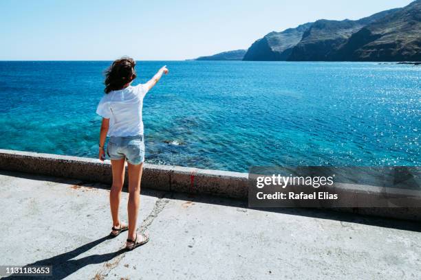 girl pointing at the horizon from the breakwater - groyne ストックフォトと画像