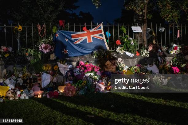 Shadows are cast onto a New Zealand flag hung amongst flowers and tributes on the wall of the Botanic Gardens on March 17, 2019 in Christchurch, New...