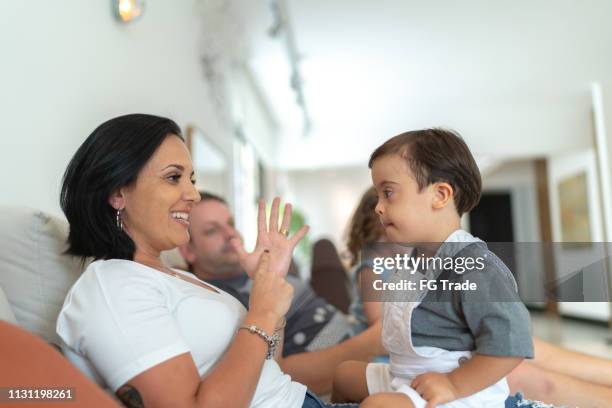 mutter gestrandung/erziehung mit ihrem down-syndrom-sohnplatz zu hause - american sign language stock-fotos und bilder