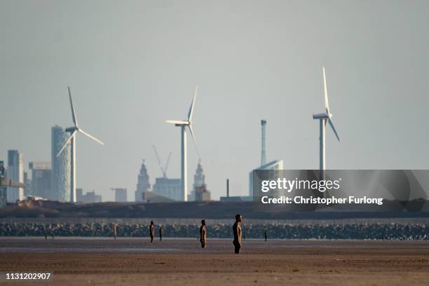 People enjoy the warm Spring weather and the Antony Gormley "Another Place" sculptures at Crosby beach on February 21, 2019 in Liverpool, England.