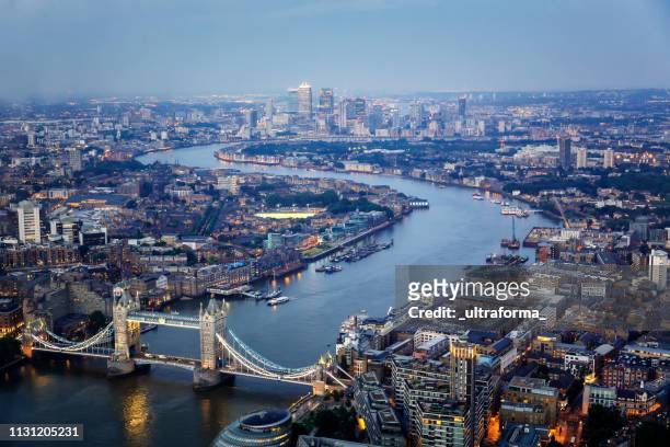 aerial view of tower bridge and canary wharf skyline at night - greater london stock pictures, royalty-free photos & images