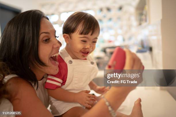 mother and down syndrome son taking a selfie after eating chocolate - mom taking photos of baby eating imagens e fotografias de stock