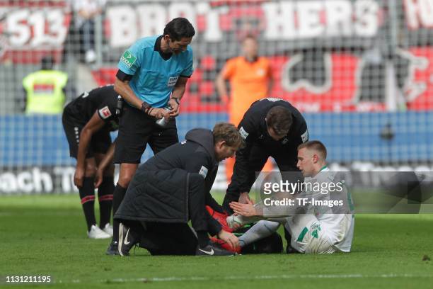 Johannes Eggestein of Werder Bremen receives medical treatment and referee Deniz Aytekin looks on during the Bundesliga match between Bayer 04...