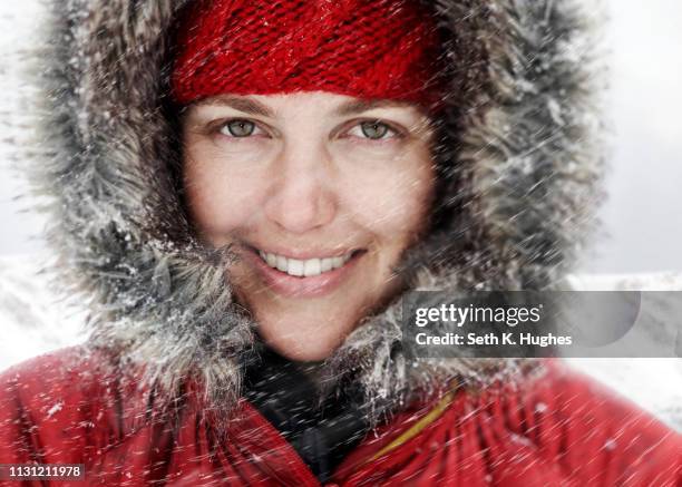 close up portrait of young woman in red hood in snow - landskap stockfoto's en -beelden