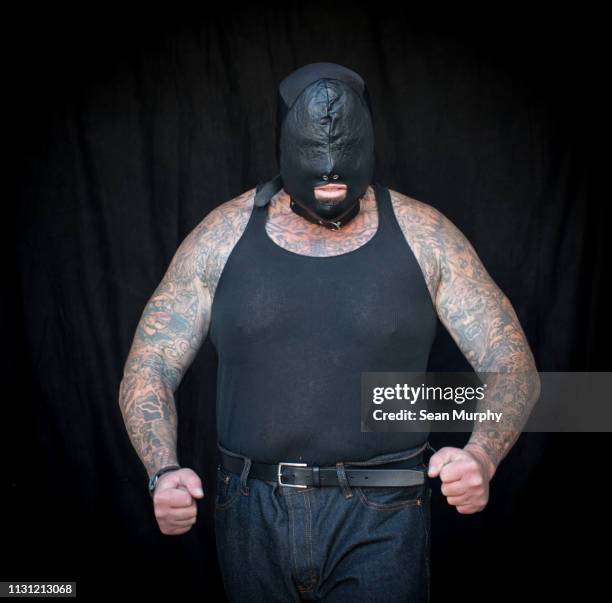 front view of mature tattooed man wearing vest and face mask - mask confrontation stock pictures, royalty-free photos & images