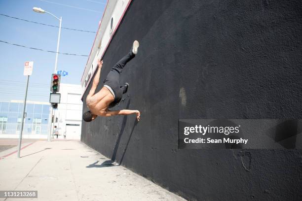 man running up wall, demonstrating parkour - le parkour fotografías e imágenes de stock