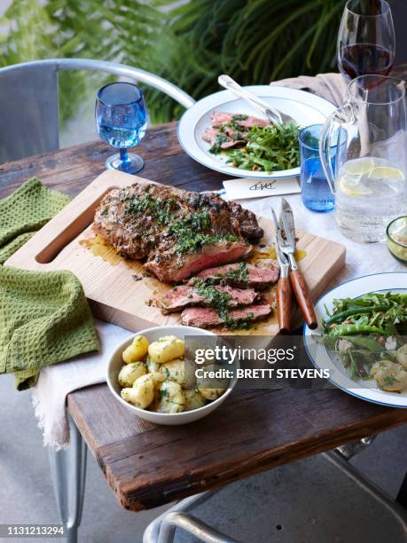 dinner table with barbecued herb crust lamb and spring greens - all australian dinner fotografías e imágenes de stock