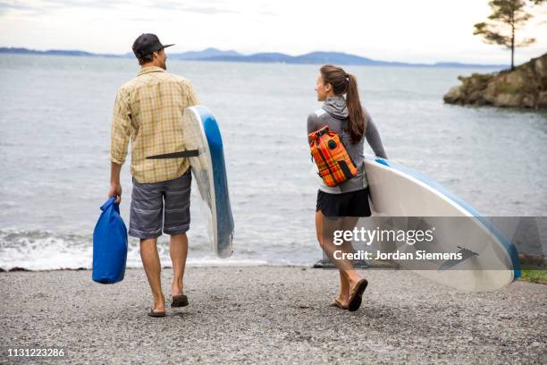 a couple on a stand up paddle board adventure. - sup stockfoto's en -beelden