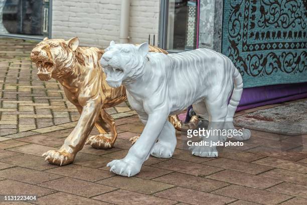 golden and white stone tigers on the street - animal sculpture stock pictures, royalty-free photos & images