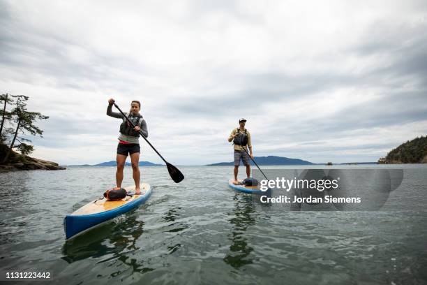 a couple on a stand up paddle board adventure. - paddle board men imagens e fotografias de stock
