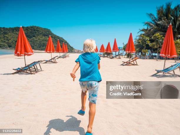 boy running on the beach - red parasol stock pictures, royalty-free photos & images