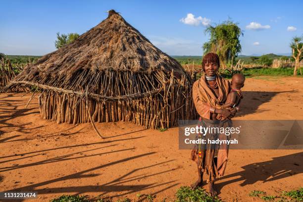 kvinna från hamer stam som bär sitt barn, etiopien, afrika - african village hut bildbanksfoton och bilder