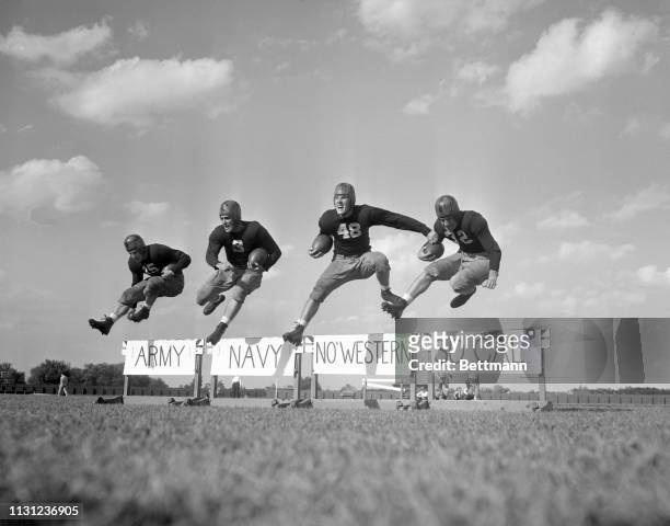 These hurdles are easy to take in practice sessions, but Steve Juzwik, Right Halfback; Robert Hargraves, Quarterback; Angelo Bertelli, Left Halfback,...