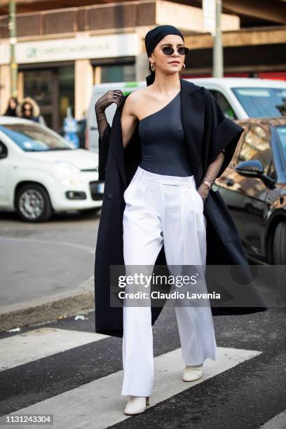Caro Daur, wearing a black coat, white pants, sunglasses and a black shirt shoulder, is seen outside Max Mara on Day 2 Milan Fashion Week...