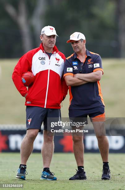 John Longmire, coach of the Swans, speaks with Leon Cameron, coach of the Giants, during the AFL pre-season practice match between the Greater...