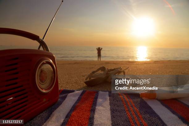 bekijk verleden radio, boek en sandalen aan vrouw op het strand - radio stockfoto's en -beelden