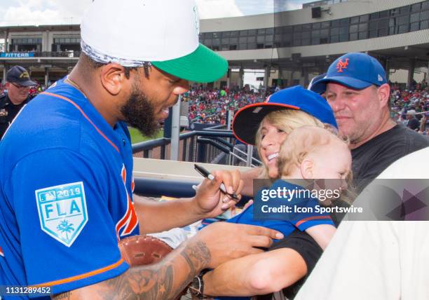 New York Mets infielder Dominic Smith autographs a baby's onesie for a fan during an MLB spring training game between the New York Mets and the...