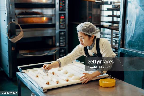mittelerwachsene frau backen brot in einer industrieküche - small business people working in asia stock-fotos und bilder
