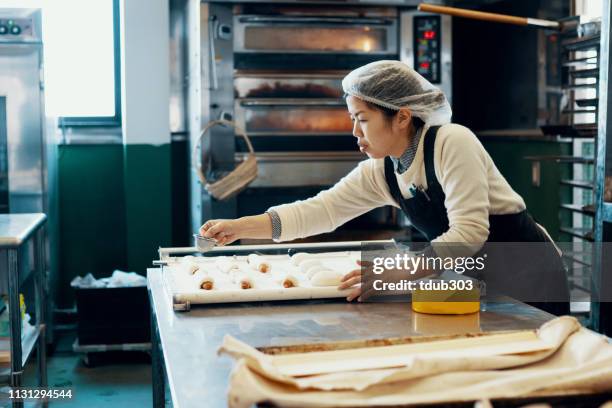 ミッドアダルト女性は、工業用キッチンでパンを焼く - 郷土料理　日本 ストックフォトと画像