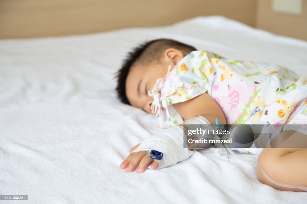 Aziatische baby jongen slapen op bed met infusie ingesteld op kind afdeling in het ziekenhuis. Kinderen met besmettelijke ziekten IPD, invasieve pneumokokken ziekte concept. Infant model een jaar zes maanden