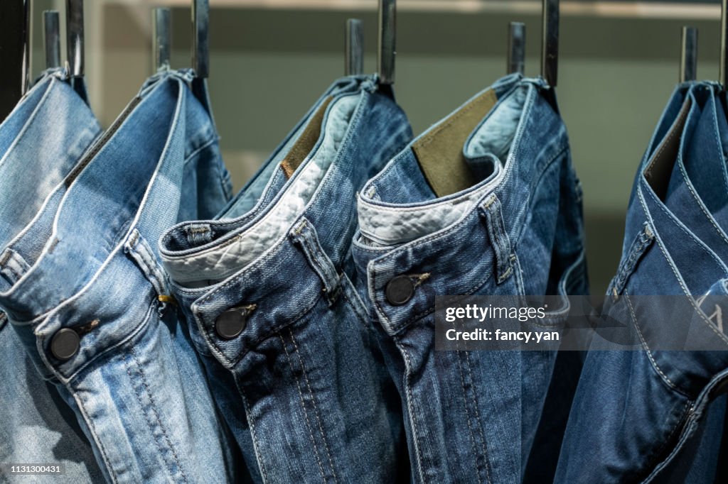 Close up of jeans hanging on clothe sack in a row