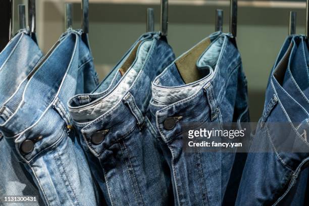 close up of jeans hanging on clothe sack in a row - denim stockfoto's en -beelden