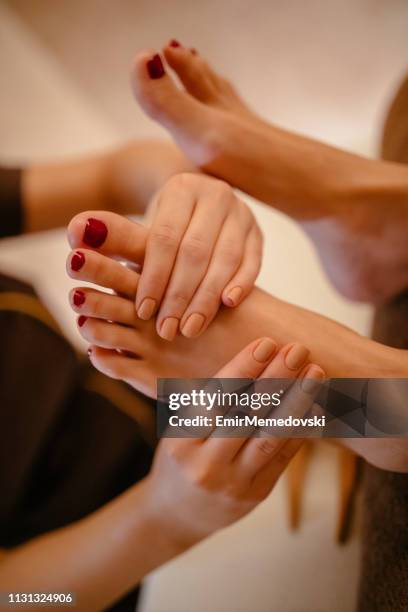 jeune femme ayant le massage relaxant de pied dans le salon de beauté - réflexologie photos et images de collection