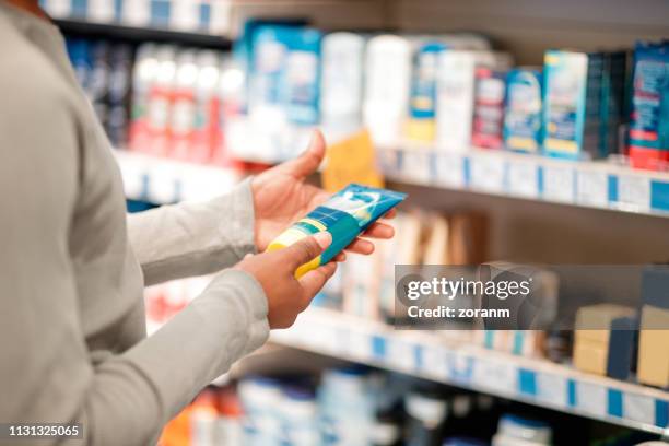 man choosing hair product in department store - beauty store stock pictures, royalty-free photos & images