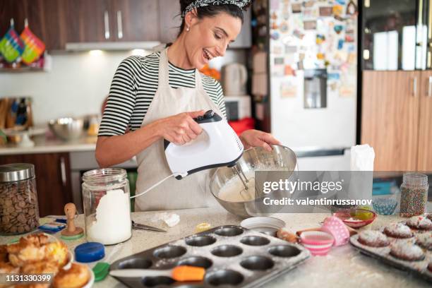 pastelero mujer haciendo deliciosa crema para cupcakes - mujer cocinando fotografías e imágenes de stock