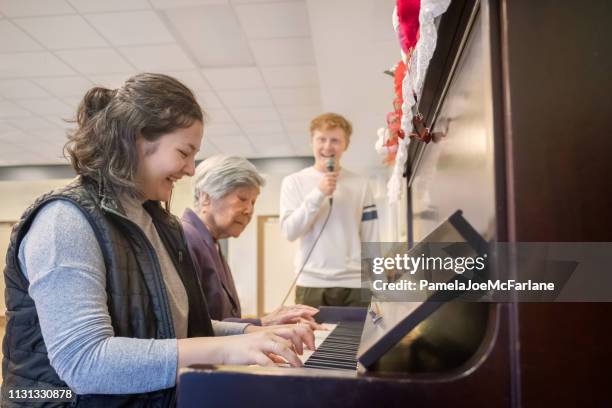 multi-generation family and friends playing piano and singing together - duet stock pictures, royalty-free photos & images