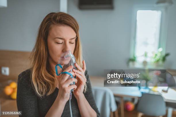junge frau mit einem asthma-inhalator - atmungsorgan stock-fotos und bilder
