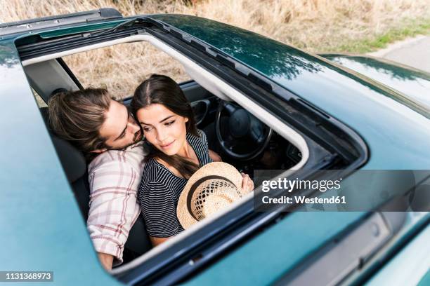 affectionate young couple in a car seen through sunroof - sunroof stock pictures, royalty-free photos & images