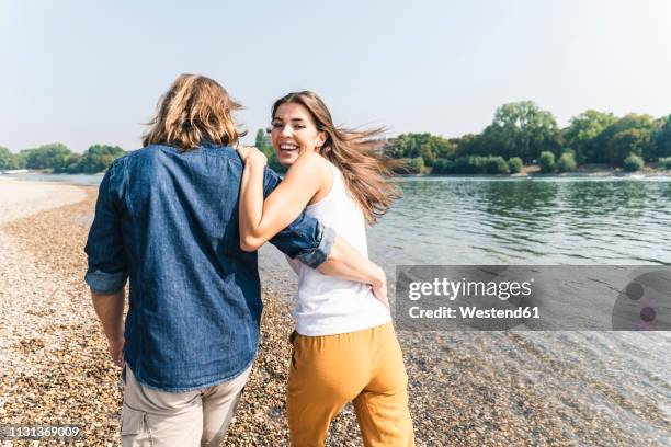 happy young couple in love walking at the riverside - turning back stock pictures, royalty-free photos & images