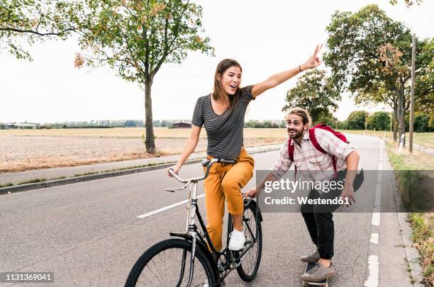 happy young couple with bicycle and skateboard on country road - leisure equipment fotografías e imágenes de stock