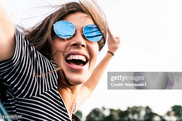 carefree young woman leaning out of car window screaming - long live our independence stock pictures, royalty-free photos & images