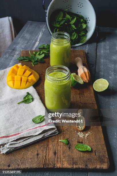 glasses of spinach smoothie with mango, lime juice and hemp seed - mango smoothie stock pictures, royalty-free photos & images