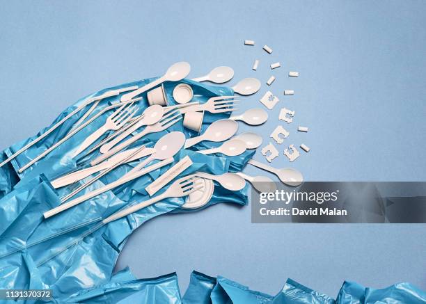 Single-use plastic objects arranged resemble a wave breaking in a sea of bags.